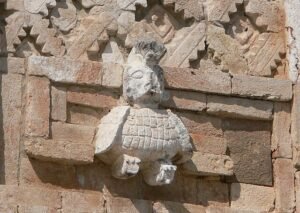 A Quetzal adoring a Mayan building in Uxmal, Mexico.