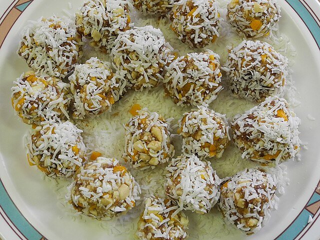 Cashew-cardamom balls, sprinkled with coconut shavings. c/o Douglas P Perkins, wikicommons.