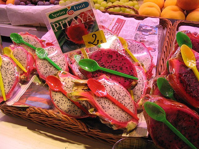 Varieties of Dragon Fruit for sale - together with plastic spoons used to scoop out the flesh. c/o Jordiferrer, wikicommons.
